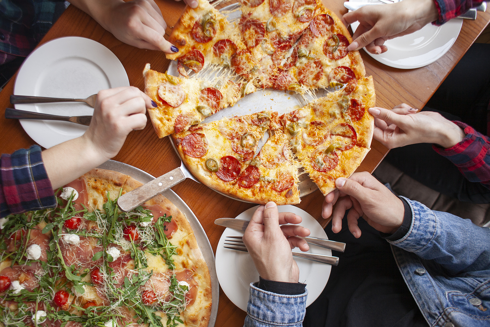 young couple sits in a pizzeria and eats pizza, a guy and a girl dine fast food, smile and relax in a restaurant